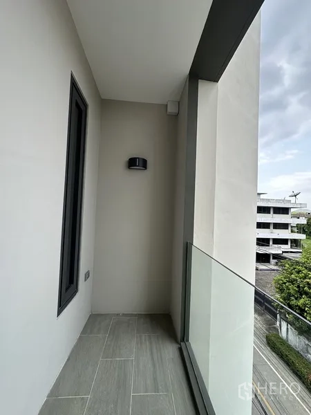 家庭办公室 for rent or sale in Suan Luang, Bangkok - 狭长阳台配玻璃栏杆，望向绿意与建筑。