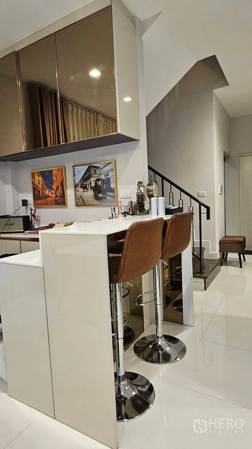 Detached House for rent in Saphan Sung, Bangkok - Breakfast bar with white countertop and two leather stools near stairs.
