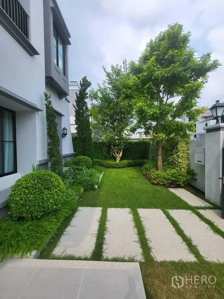 Detached House for rent in Saphan Sung, Bangkok - Landscaped side garden with lawn, trees and paved walkway.