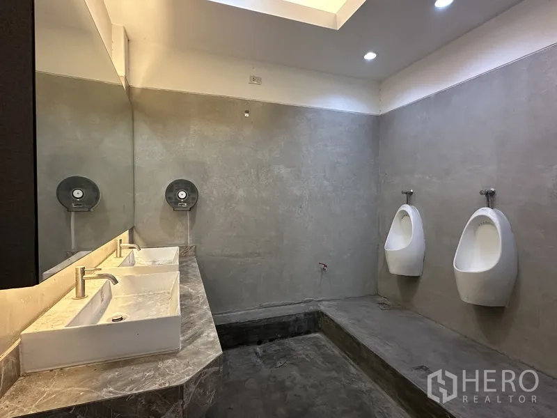Retail Space for rent in Bang Rak, Bangkok - Men’s restroom with twin urinals, sinks, large mirror, and concrete finish.