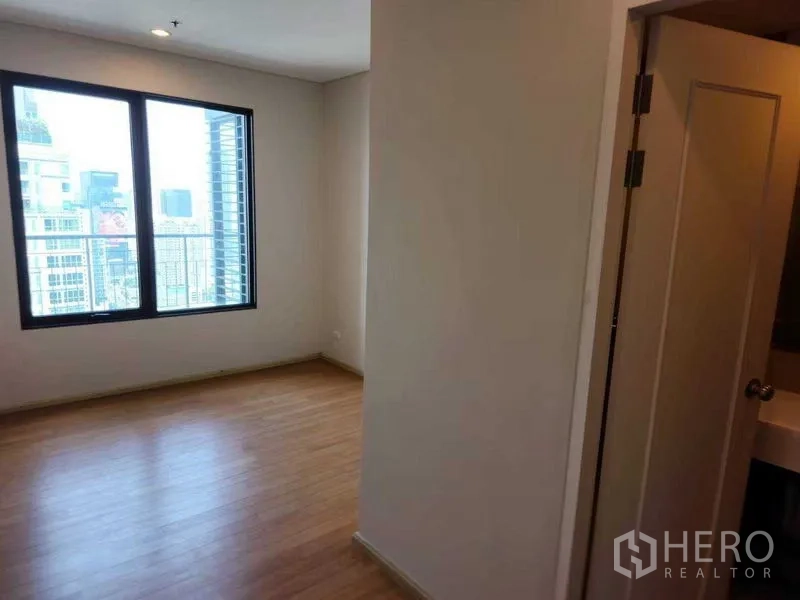 公寓 出租在Ratchathewi, Bangkok - 角落卧室，城市景观窗，旁有套内卫浴的门。