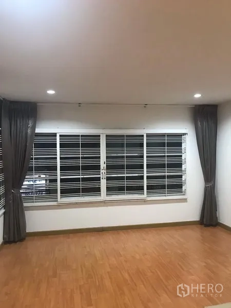 独立式住宅 出租在Din Daeng, Bangkok - 明亮房间，大窗配防盗格栅与深色窗帘，木纹地板。