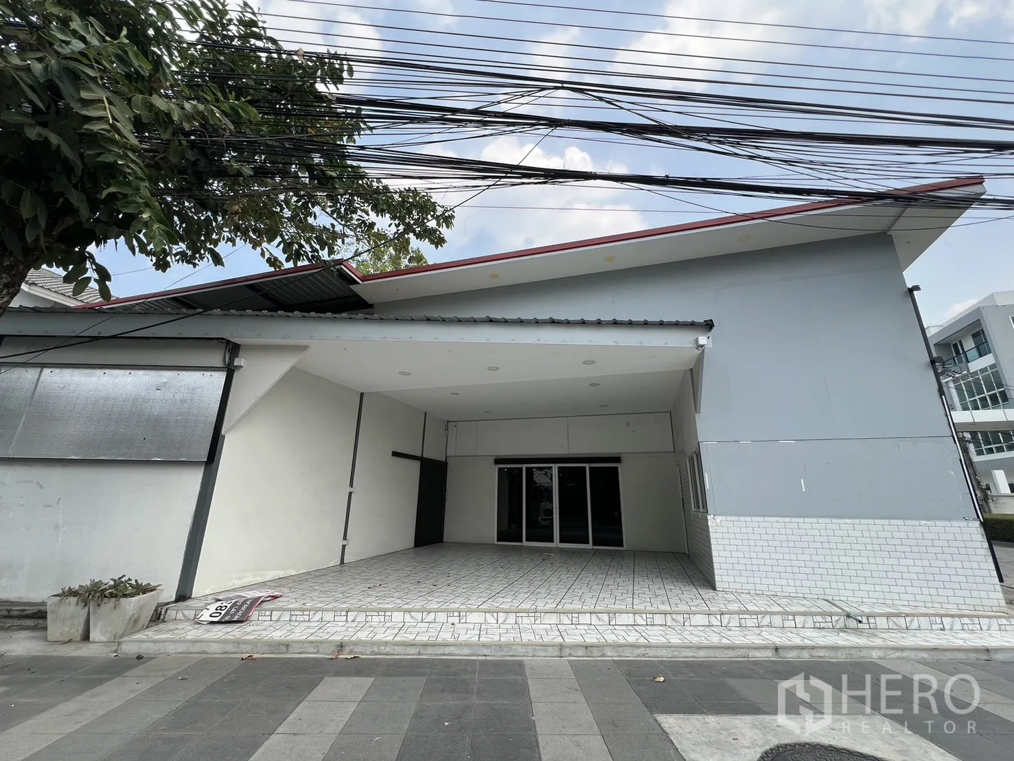 零售空间 for rent in Bueng Kum, Bangkok - 临街零售建筑，带遮雨门廊、斜坡屋顶与铺装前院。