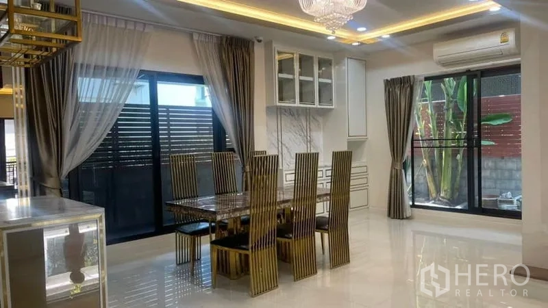 Detached House for rent or sale in Prawet, Bangkok - Open-plan dining room with gold chairs, large windows and access to the garden.