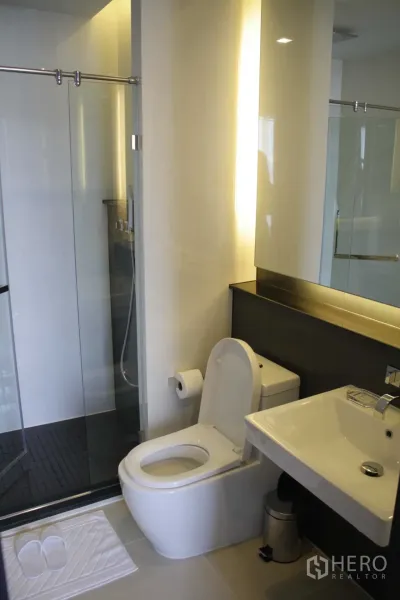 คอนโด ให้เช่าในHuai Khwang, Bangkok - ห้องน้ำสมัยใหม่พร้อมตู้ shower กระจก อ่างล้างหน้าแบบแขวน และชักโครก แสงไฟอบอุ่น