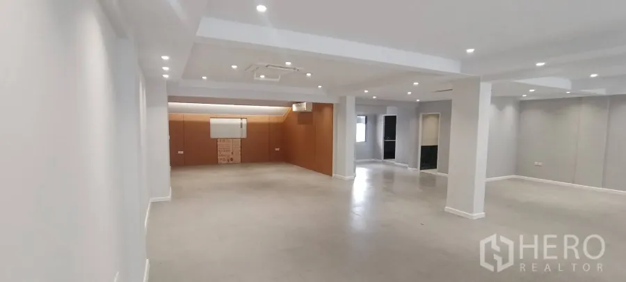 Office Space for rent in Watthana, Bangkok - Long open-plan hall with recessed lighting and a wood-paneled end wall.