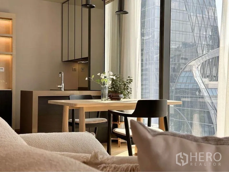 Condominium for rent in Pathum Wan, Bangkok - Dining table by floor-to-ceiling windows overlooking the Bangkok skyline near BTS Chitlom.