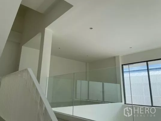 Home Office for rent in Don Mueang, Bangkok - Minimalist upper floor with glass railing and a wide window for natural light.
