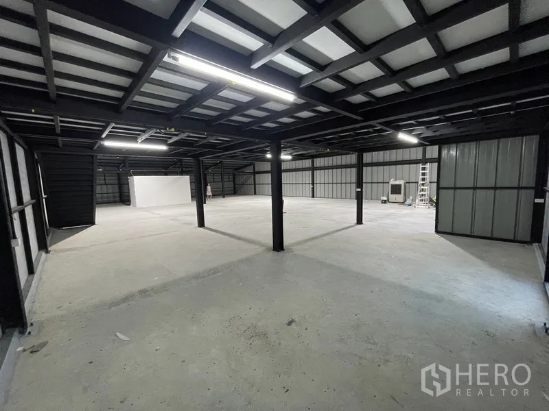 Warehouse for rent in Bueng Kum, Bangkok - Large open-plan mezzanine level under a metal roof with LED lighting and concrete flooring.