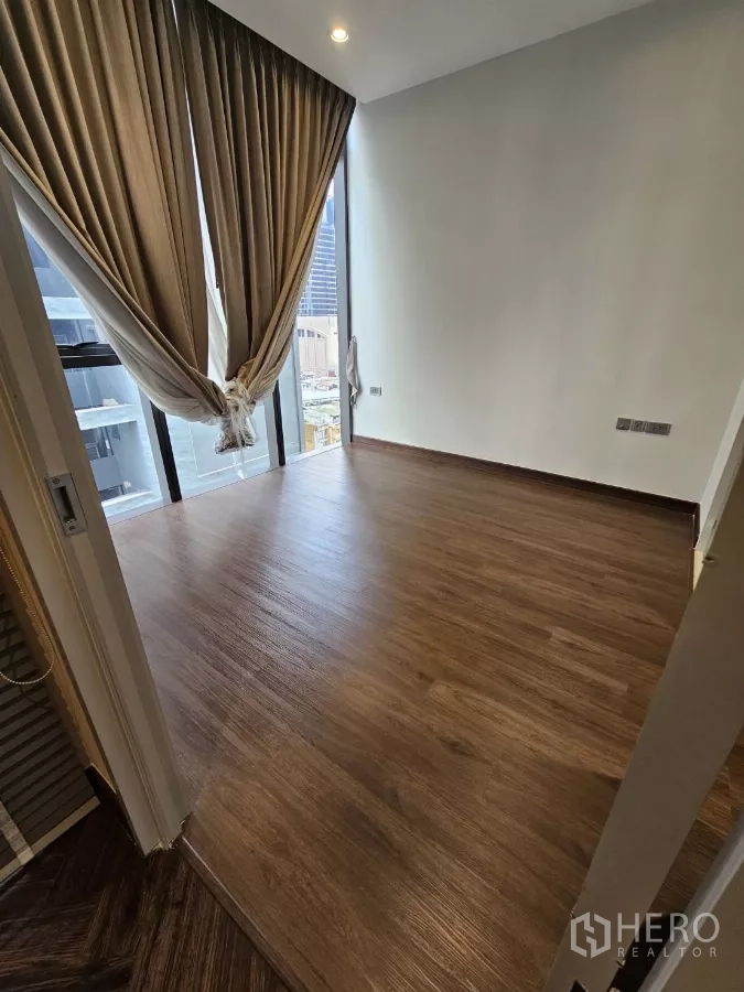 公寓 出租在Watthana, Bangkok - 转角卧室，木地板、高帘与大面积窗户，视野开阔。