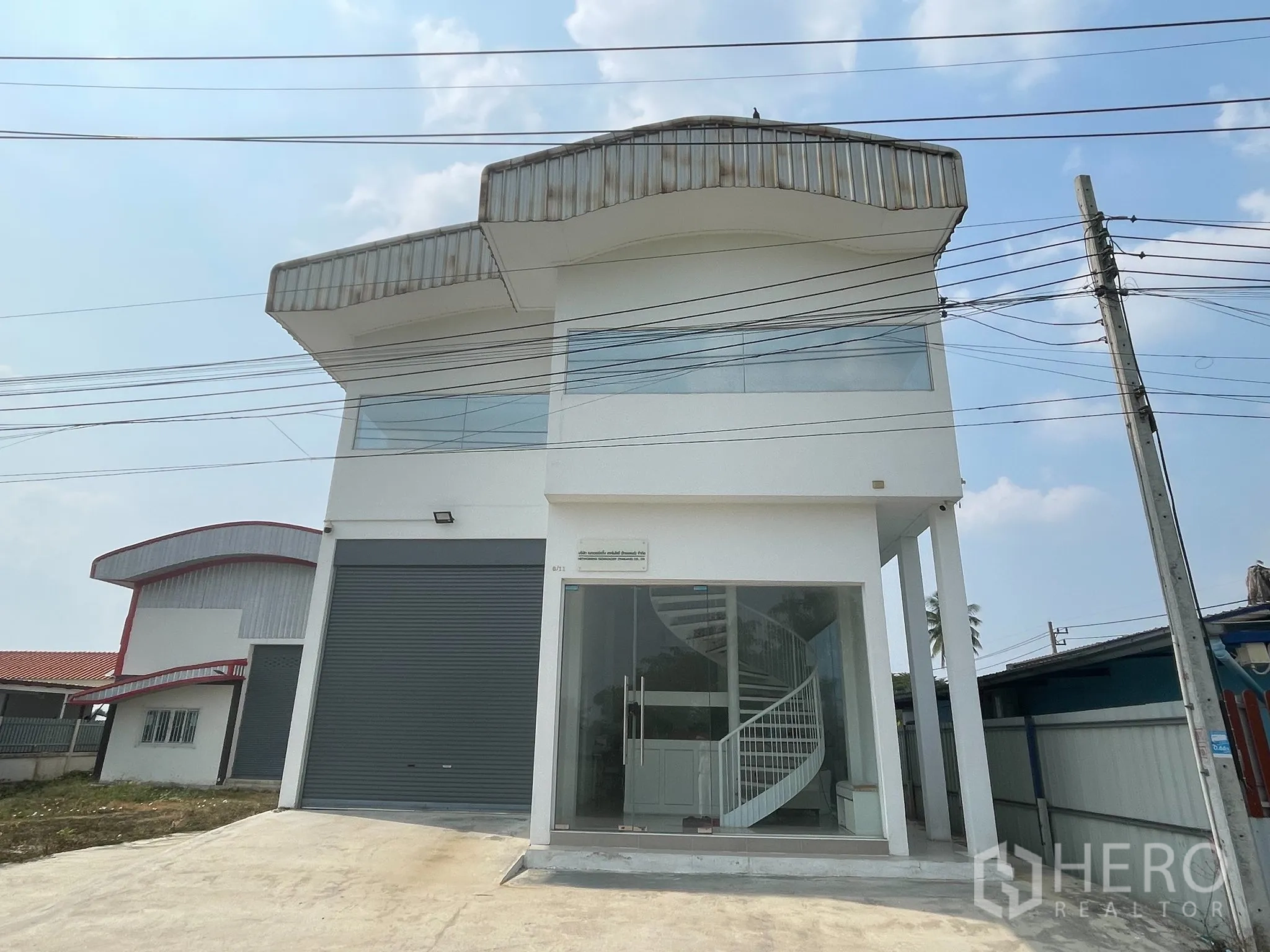 仓库 for sale in Lat Lum Kaeo, Pathum Thani - 两层白色仓库，前方为玻璃办公区，配电动卷帘门和宽阔车道。