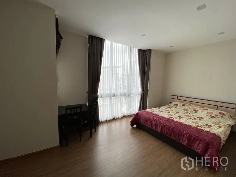 Townhouse for rent in Suan Luang, Bangkok - Secondary bedroom with floor-to-ceiling sheer curtains and a king-size bed.