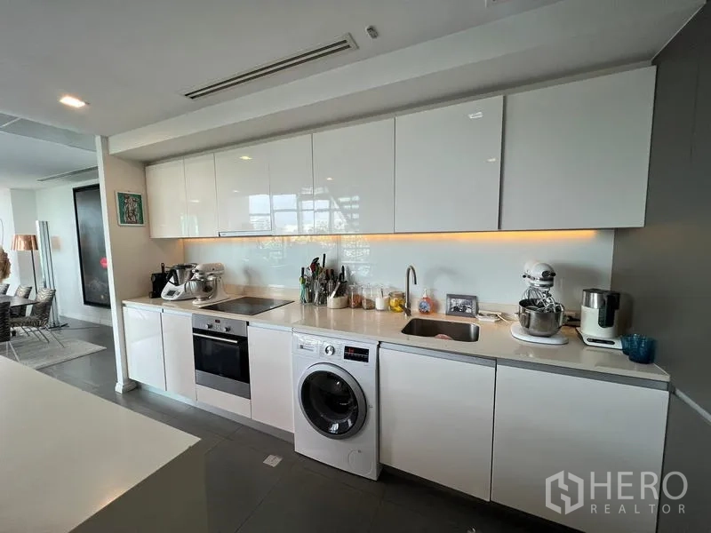 Condominium for sale in Khlong San, Bangkok - Sleek white linear kitchen with built-in oven, washer, and ample cabinets.