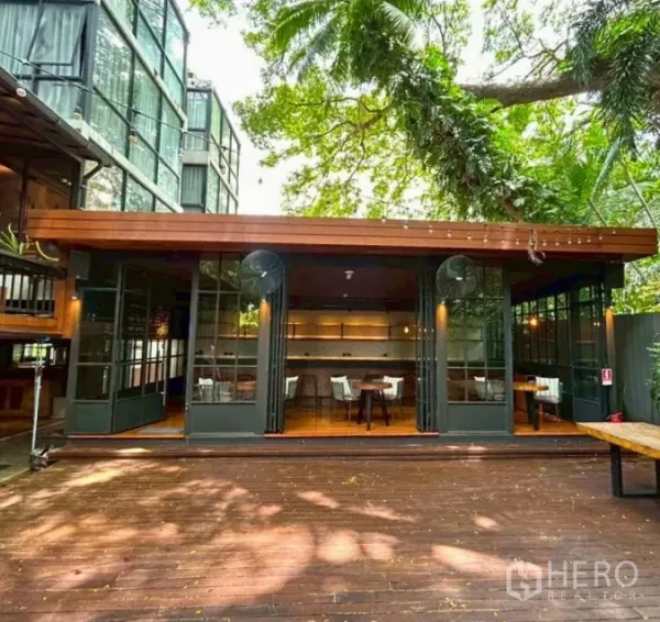 Retail Space for rent in Yan Nawa, Bangkok - Leafy courtyard frontage with folding glass doors opening to a wooden deck at a restaurant-ready retail space.