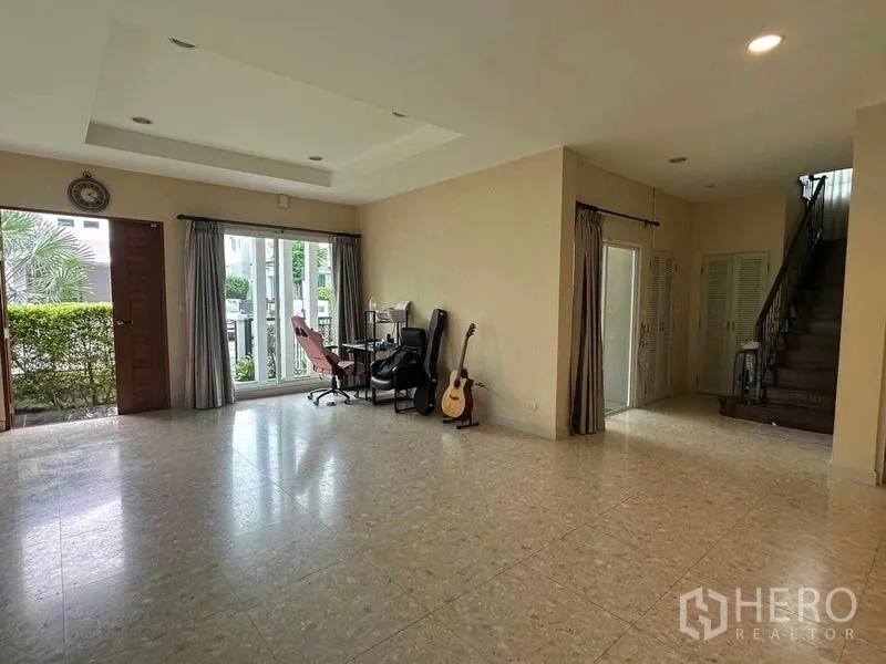 独立式住宅 出售在Saphan Sung, Bangkok - 明亮客厅，推拉门通向花园，旁有楼梯上二层。