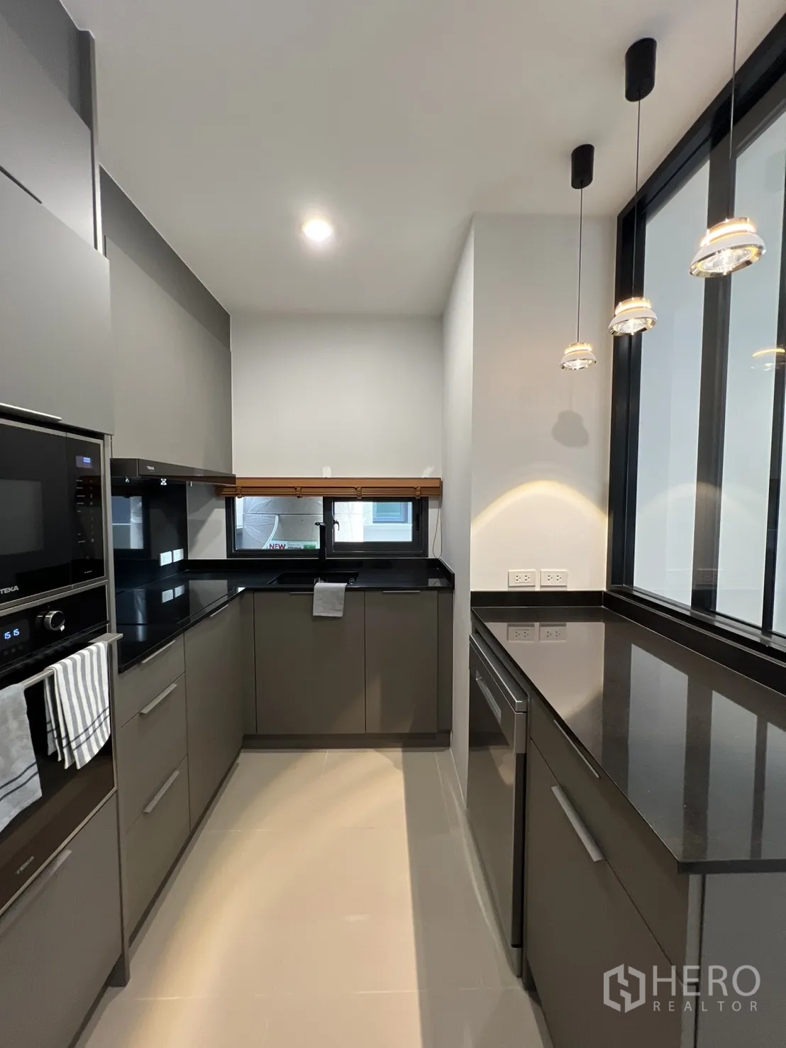独立式住宅 出租在Prawet, Bangkok - U形紧凑厨房，带窗与充足收纳。