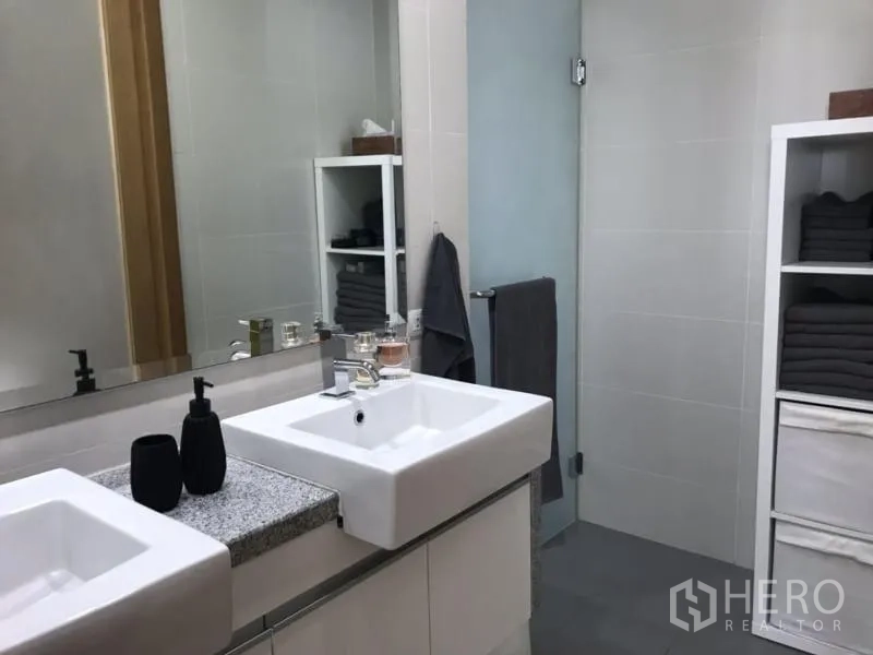 Condominium for rent in Khlong Toei, Bangkok - Contemporary bathroom with double square basins and a large mirror.