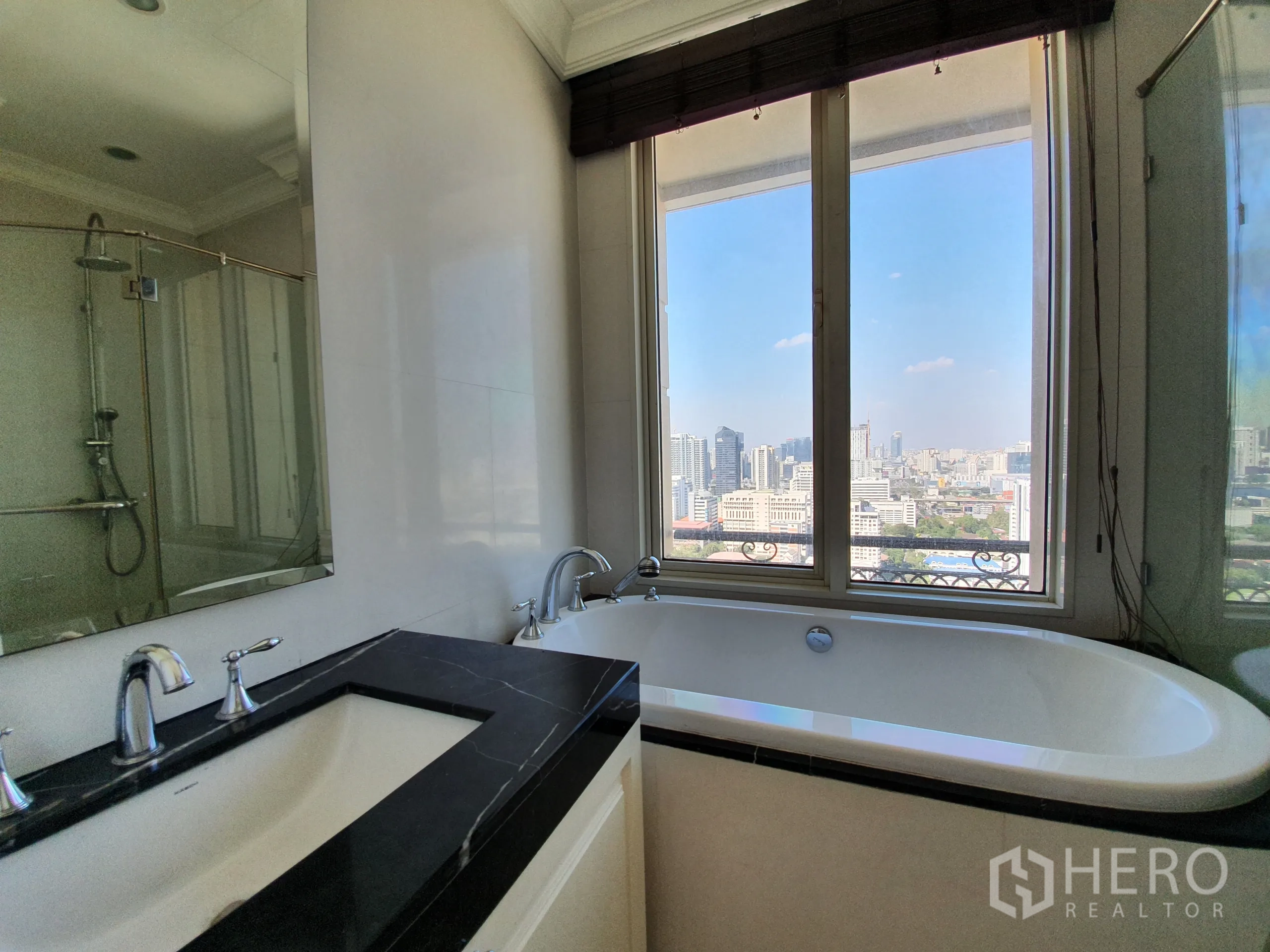 公寓 出租在Watthana, Bangkok - 浴室设窗边浸泡浴缸、独立淋浴与黑色台面洗手台和大镜。