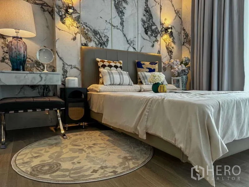 Condominium for rent - Primary bedroom with upholstered bed, bedside table and dramatic marble wall.