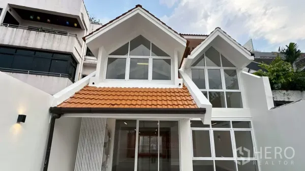 Home Office for rent in Watthana, Bangkok - White gabled exterior with large windows and orange roof tiles at the property entrance.