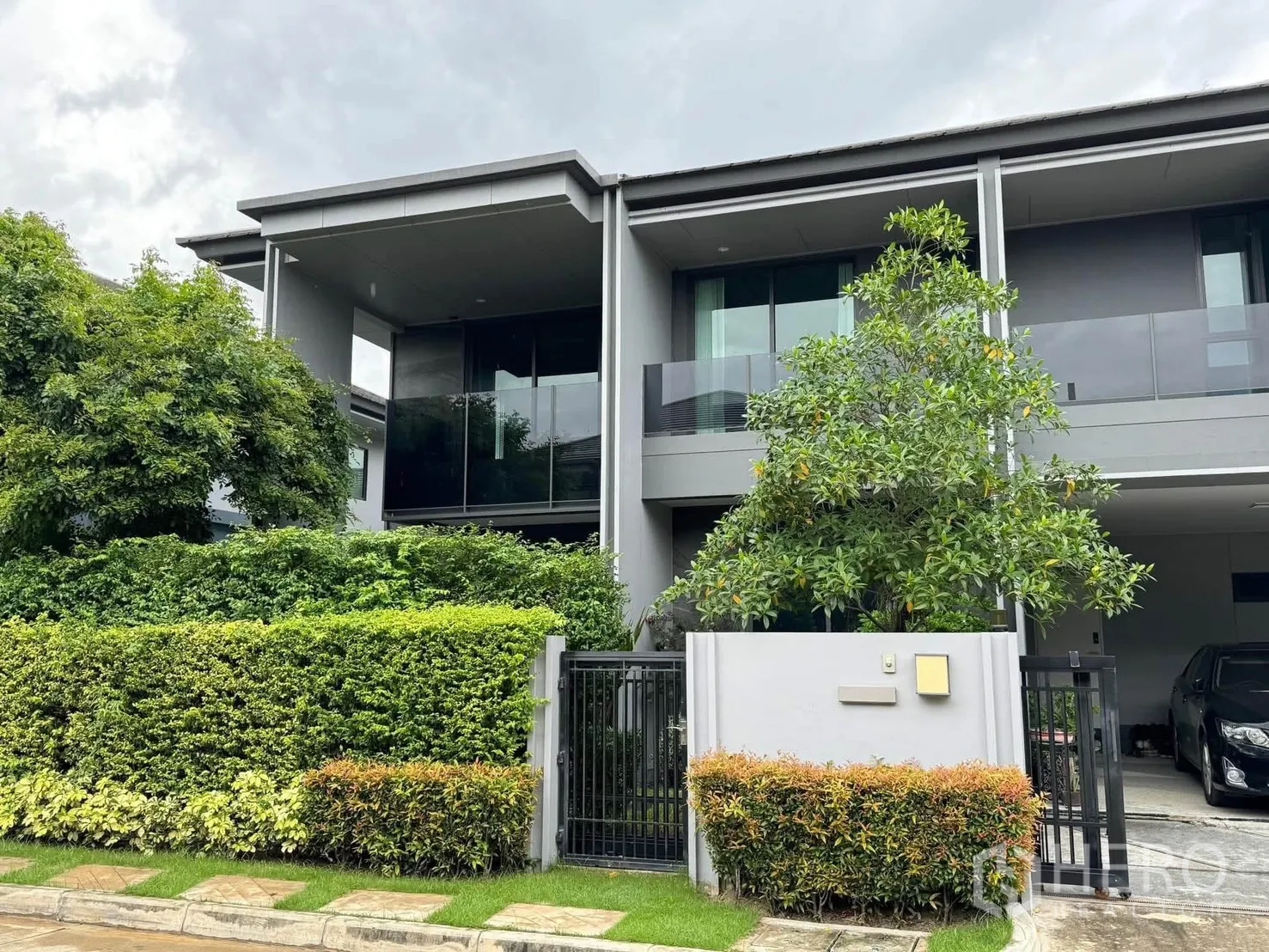 Detached House for rent in Bang Kapi, Bangkok - Modern two-storey detached house exterior with balcony, gate, and greenery.