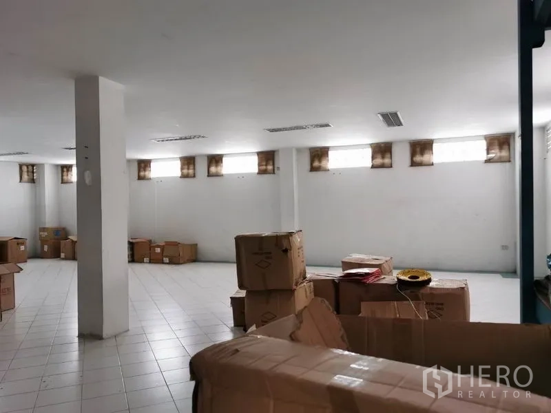 办公空间 出租在Khlong San, Bangkok - 仓库式房间，纸箱沿墙堆放，高窗带来自然光。