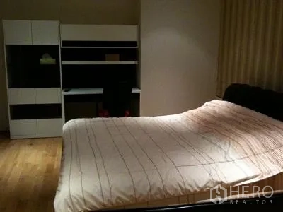 Condominium for rent or sale in Khlong Toei, Bangkok - Second bedroom with large bed, study desk, shelves, and wood flooring.