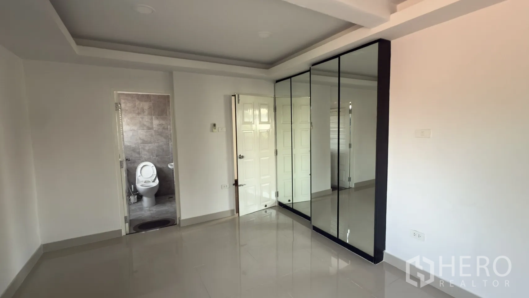 联排别墅 for rent in Watthana, Bangkok - 卧室带镜面衣柜与灰色瓷砖的套内卫生间。