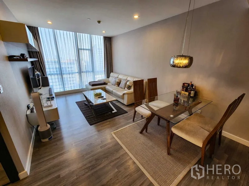 Condominium for rent or sale in Bang Rak, Bangkok - Living and dining space with a glass table, wood floors, and city view.