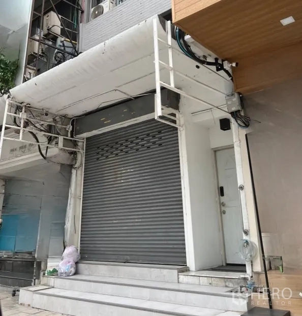 Retail Space for rent in Watthana, Bangkok - Ground-floor shopfront with closed roller shutter, white facade and raised steps on a busy Asoke street.