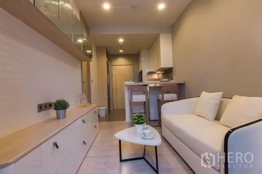 Condominium for sale in Watthana, Bangkok - Open-plan living with sofa, built-in storage and breakfast bar connecting to the kitchen.