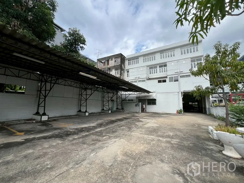 Shophouse for rent in Phra Khanong, Bangkok - Rear courtyard with covered parking bays and view of the building’s back facade.