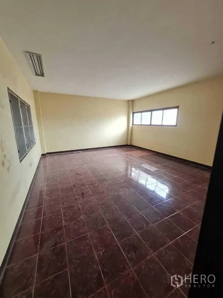 Warehouse for rent in Bang Yai, Nonthaburi - Empty office room with corner windows and dark red tiled flooring.