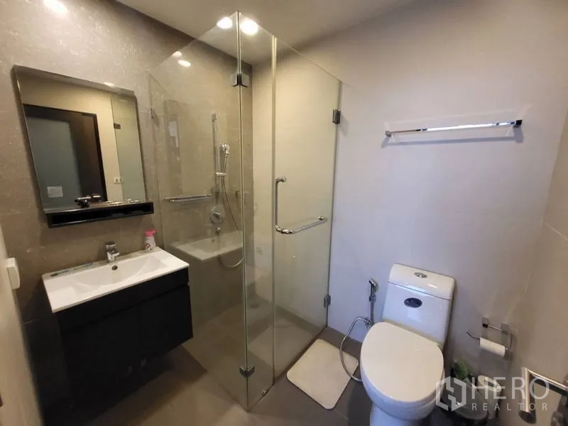 Condominium for rent or sale in Phaya Thai, Bangkok - Modern bathroom with glass-enclosed shower, vanity and toilet.