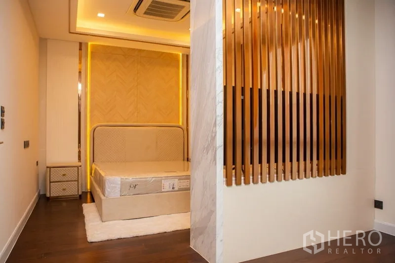 บ้าน ให้เช่าหรือขายในBangkok - ห้องนอนพร้อมหัวเตียงดีไซน์ เครื่องปรับอากาศฝังฝ้า และฉากกั้นซี่สีทอง