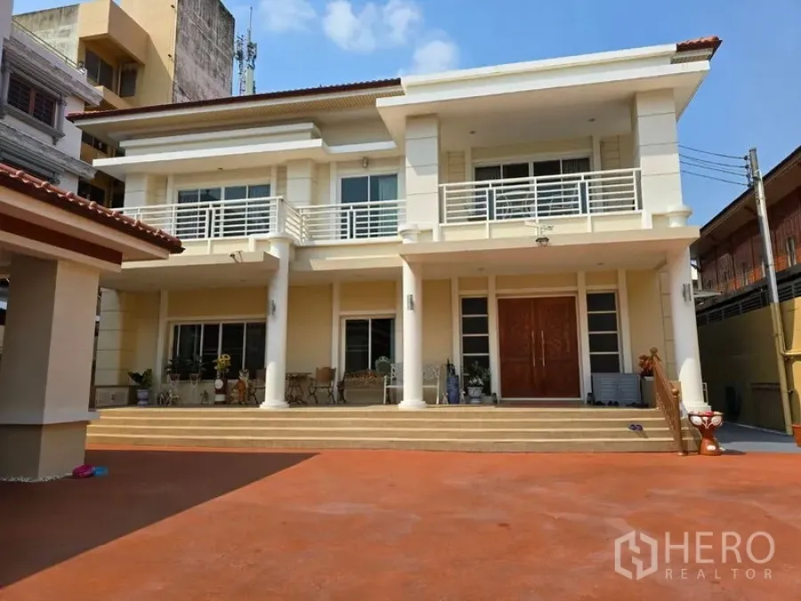 Land for sale - Front exterior showing steps, balcony railings, and expansive forecourt for parking.