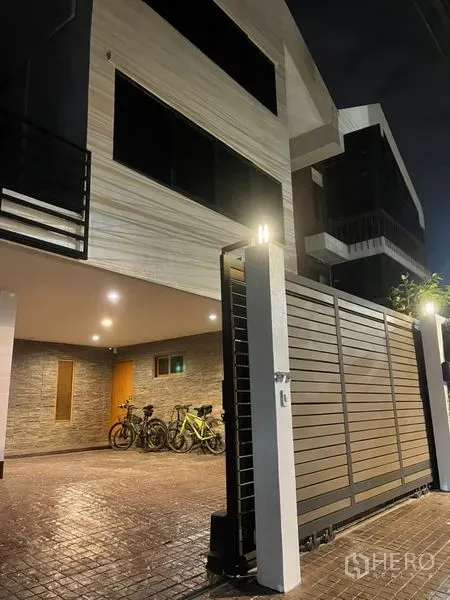 Townhouse for rent in Suan Luang, Bangkok - Modern multi-storey townhouse exterior at night with sliding gate and covered carport in Suan Luang, Bangkok.