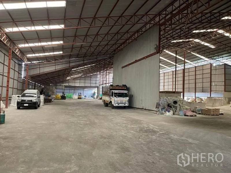 คลังสินค้า ขายในLam Luk Ka, Pathum Thani - ช่องกลางโกดัง มีรถบรรทุกจอดข้างผนังเมทัลชีทสูง พื้นที่กลับรถกว้าง
