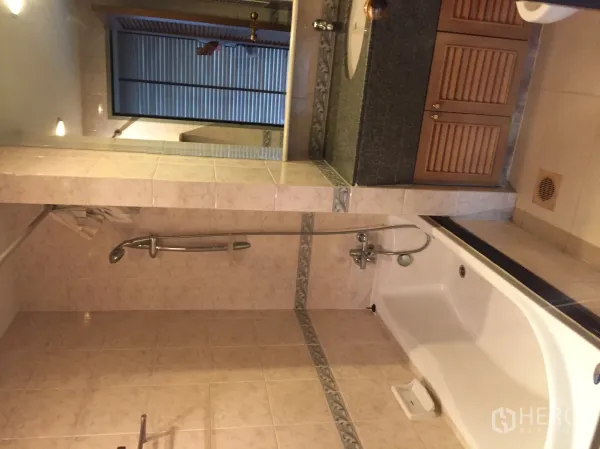 Condominium for rent in Pathum Wan, Bangkok - Tiled bathroom with bathtub, handheld shower, and a granite vanity with louvered cabinets.