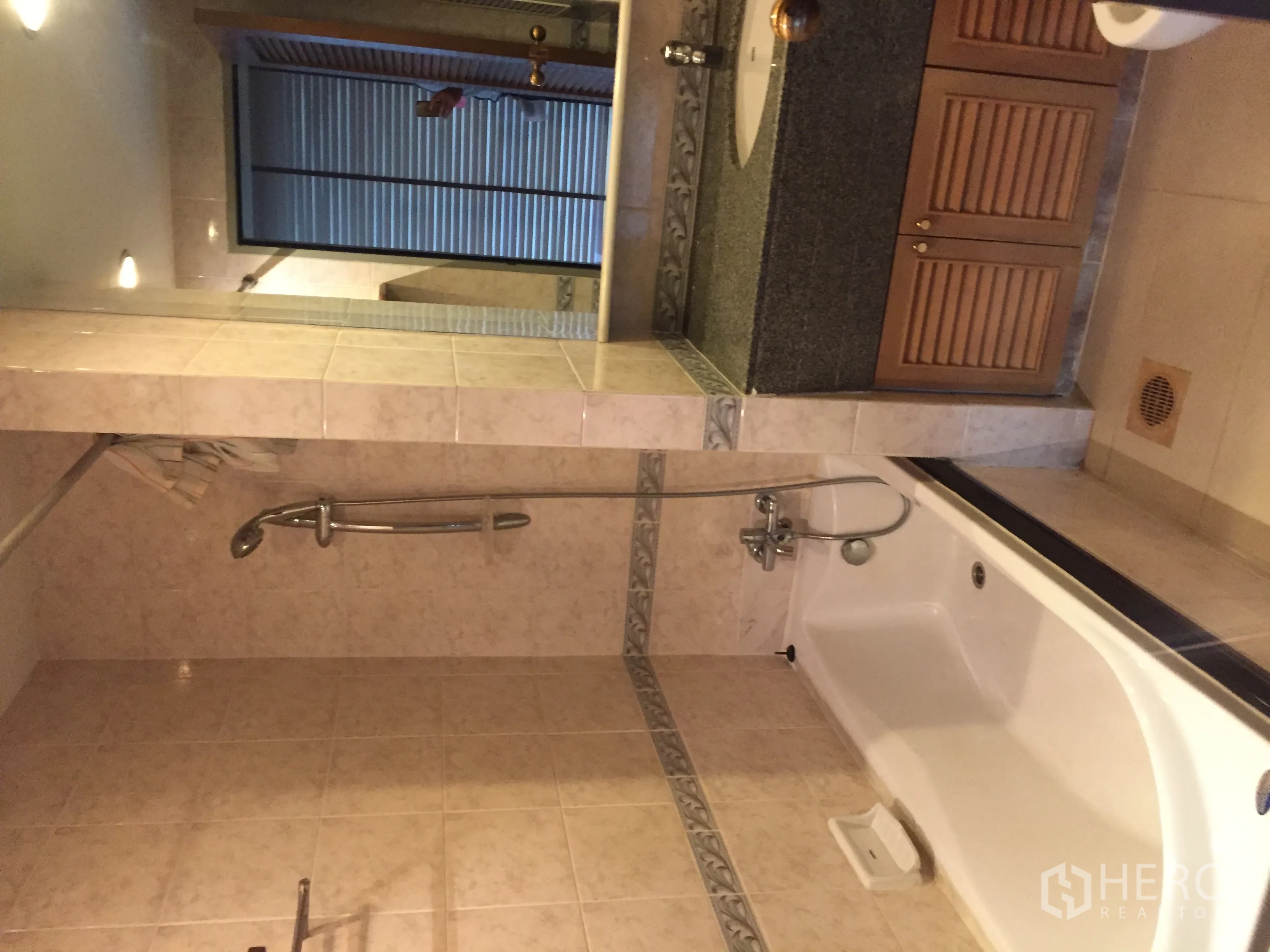 Condominium for rent in Pathum Wan, Bangkok - Tiled bathroom with bathtub, handheld shower, and a granite vanity with louvered cabinets.