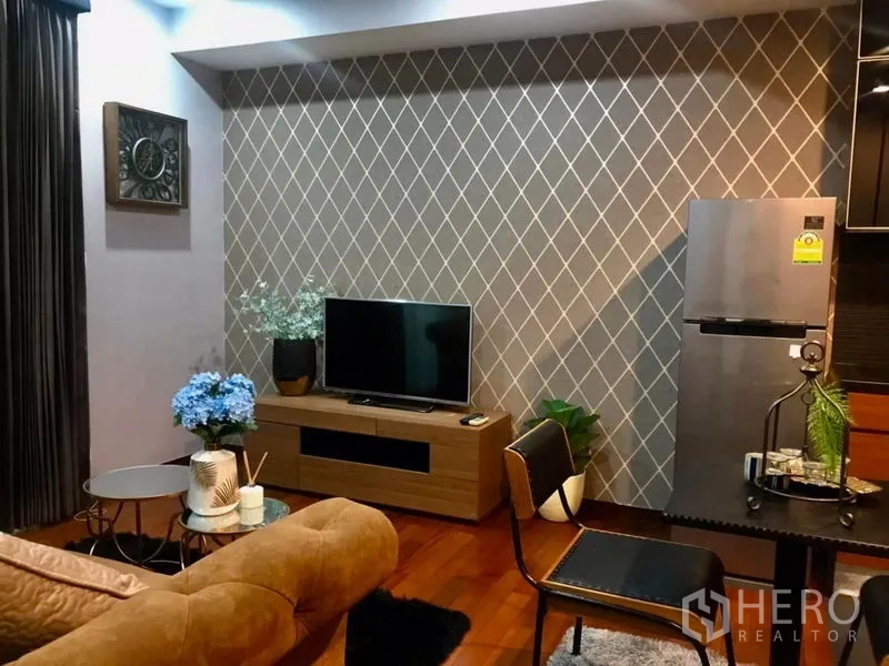 公寓 出租在Watthana, Bangkok - 舒适客厅，菱形纹理背景墙、电视柜与不锈钢冰箱。