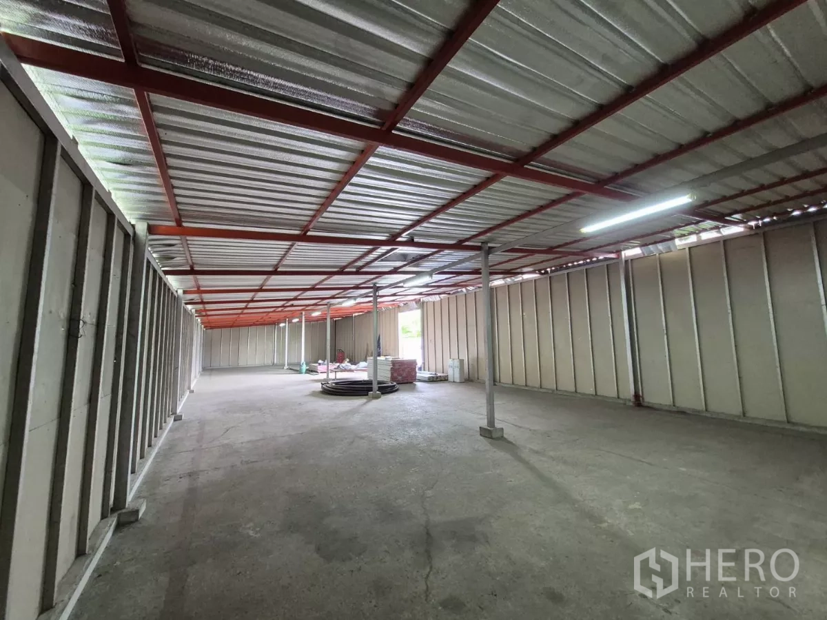 Warehouse for rent in Mueang Pathum Thani, Pathum Thani - Deep warehouse bay showing steel truss ceiling, bright lights and clear open floor space.