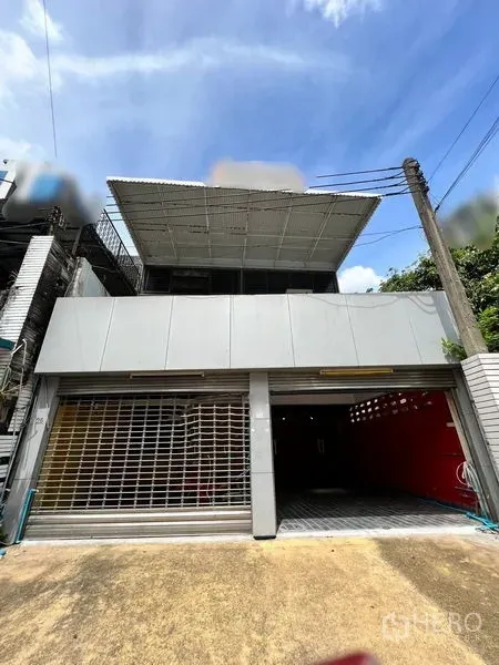 Townhouse for rent in Khlong Toei, Bangkok - Two-storey townhouse facade with wide roller doors and metal awning.