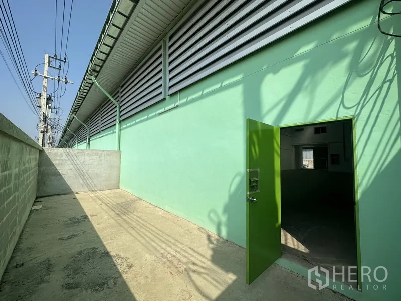 货栈 出租在Pathum Thani - 侧边私密作业区，绿色服务门与通风百叶。