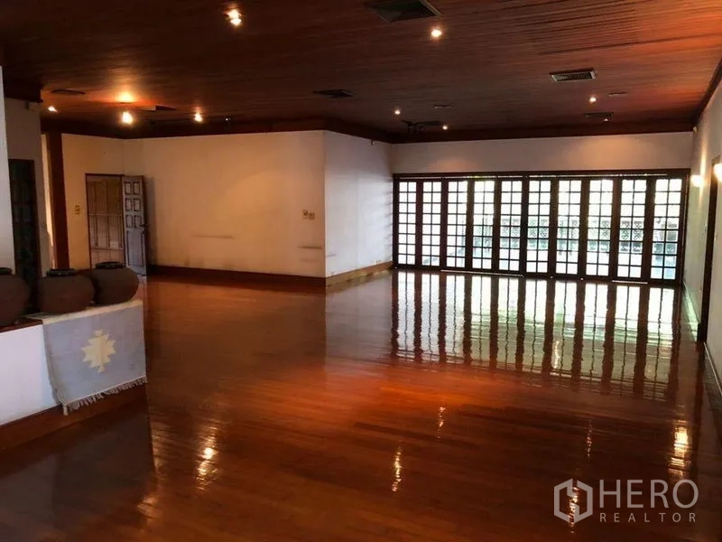 Detached House for sale in Bang Na, Bangkok - Open-plan hall with glossy timber floor, recessed lighting and full-length glass doors.