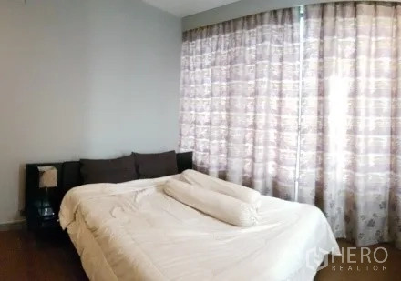 Condominium for rent in Bang Rak, Bangkok - Bright bedroom with a large window, blackout curtains and wood flooring.