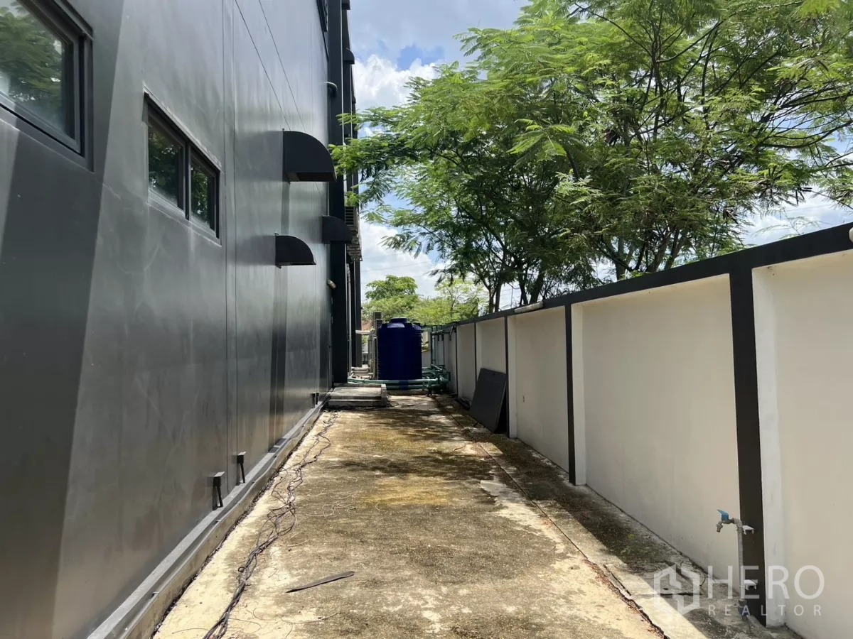 货栈 出售在Lat Krabang, Bangkok - 建筑后侧服务通道，围墙与树木成行。