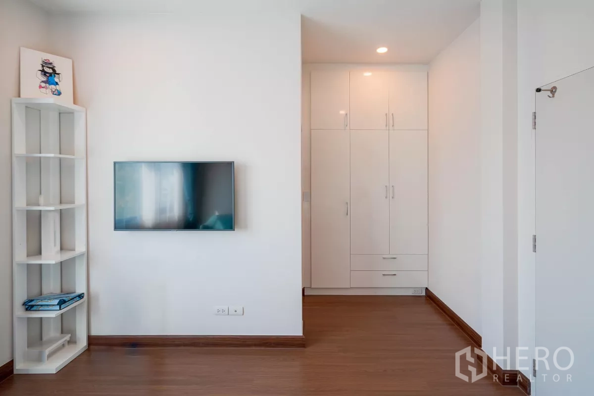 Detached House for sale in Saphan Sung, Bangkok - Bedroom wall with flat-screen TV and built-in white wardrobes.