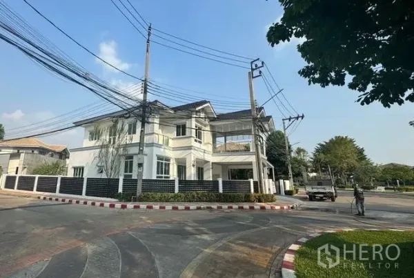 独立式住宅 出售在Pak Kret, Nonthaburi - 街角视角的白色两层住宅，围墙与转角地