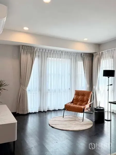 Detached House for rent or sale in Bang Phli, Samut Prakan - Sunlit sitting area with wraparound sheer curtains, recessed lighting and a leather accent chair.